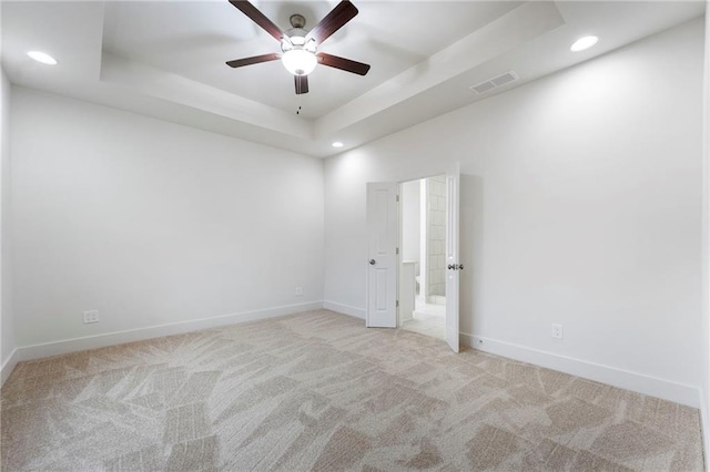 unfurnished room featuring light colored carpet, a raised ceiling, and ceiling fan