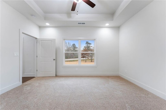 unfurnished room with a raised ceiling, carpet flooring, and ceiling fan