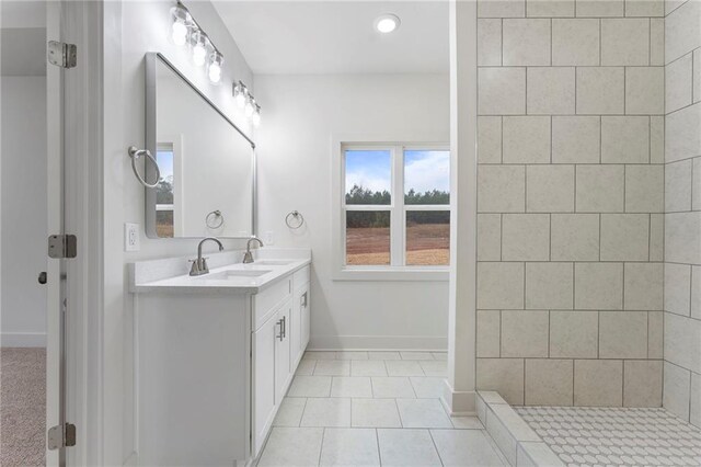 bathroom with tile patterned flooring, vanity, and tiled shower