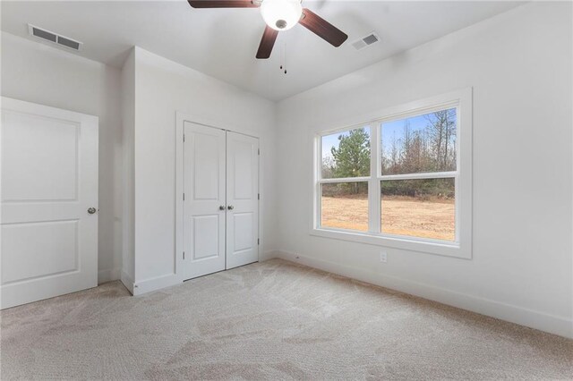 unfurnished bedroom with light colored carpet, ceiling fan, and a closet