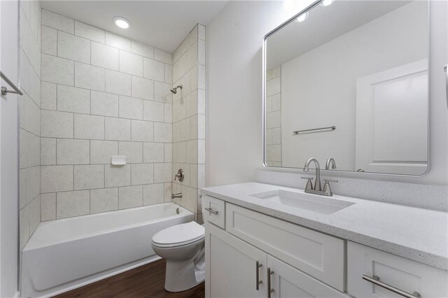 full bathroom with tiled shower / bath, wood-type flooring, toilet, and vanity