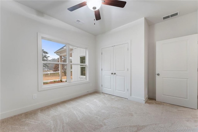 unfurnished bedroom with light carpet, ceiling fan, and a closet