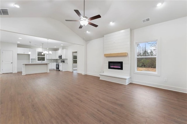 unfurnished living room with lofted ceiling, ceiling fan with notable chandelier, and dark hardwood / wood-style flooring