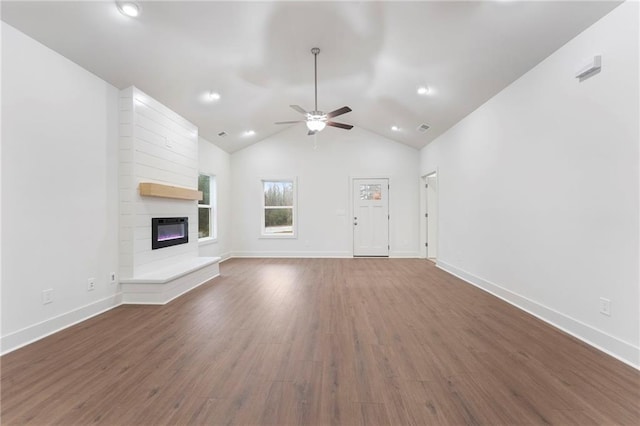 unfurnished living room featuring lofted ceiling, a large fireplace, dark hardwood / wood-style floors, and ceiling fan