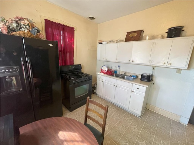 kitchen featuring visible vents, a sink, black appliances, light countertops, and white cabinetry