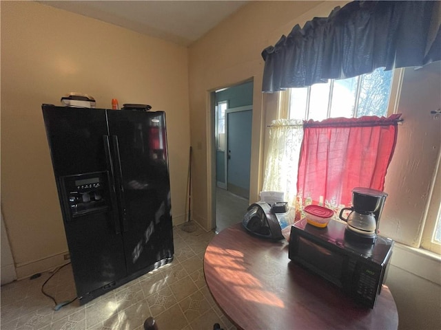 interior space featuring tile patterned flooring and black refrigerator with ice dispenser