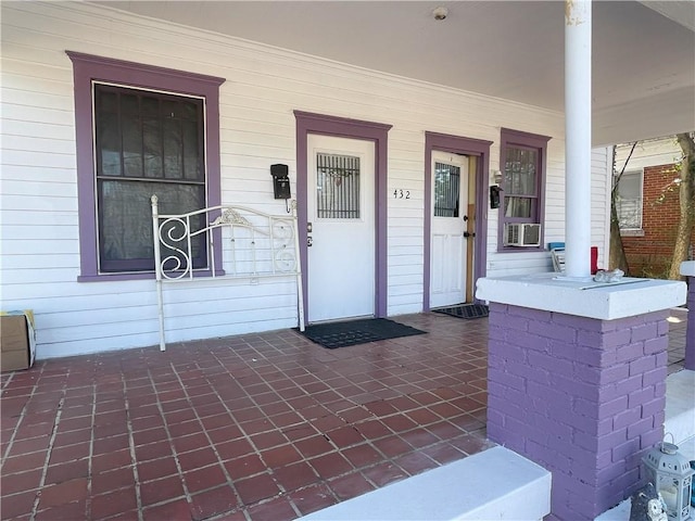 view of exterior entry featuring covered porch and cooling unit