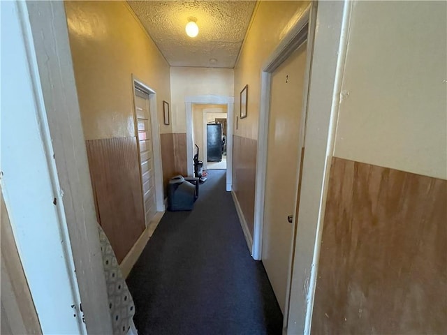 hallway with wainscoting, carpet floors, and a textured ceiling