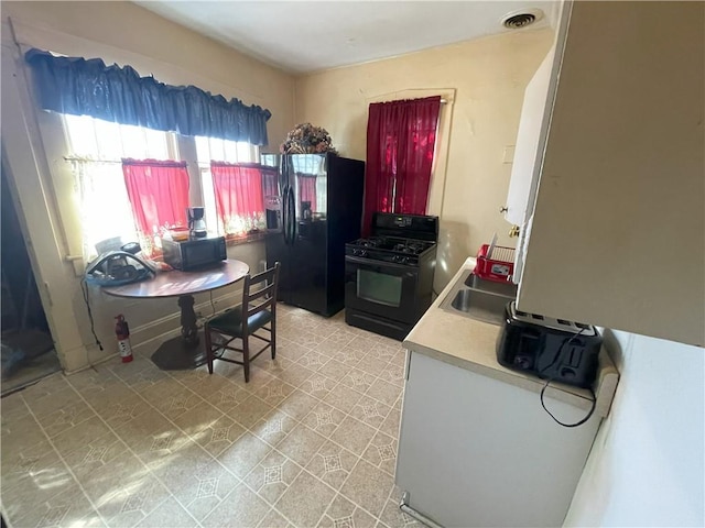 kitchen featuring visible vents, baseboards, light countertops, black appliances, and a sink