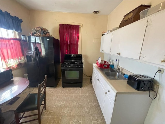 kitchen with visible vents, black appliances, a sink, white cabinetry, and light countertops