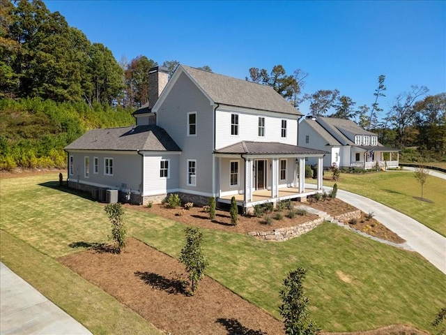 farmhouse inspired home featuring covered porch, a chimney, central AC, and a front yard