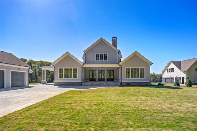 rear view of property with a yard, a chimney, and concrete driveway