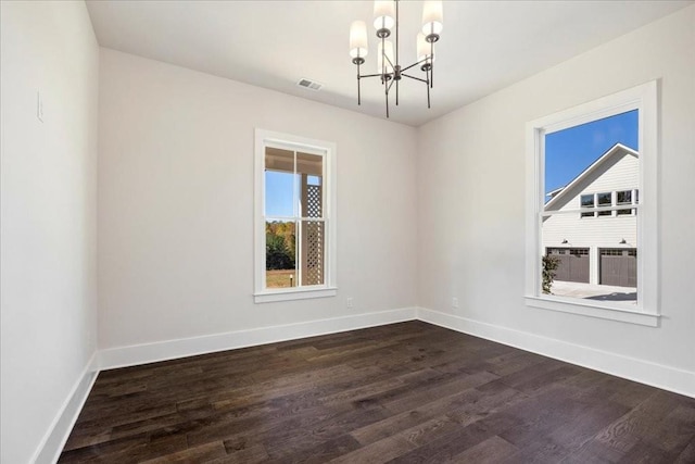 spare room with baseboards, visible vents, a chandelier, and dark wood finished floors