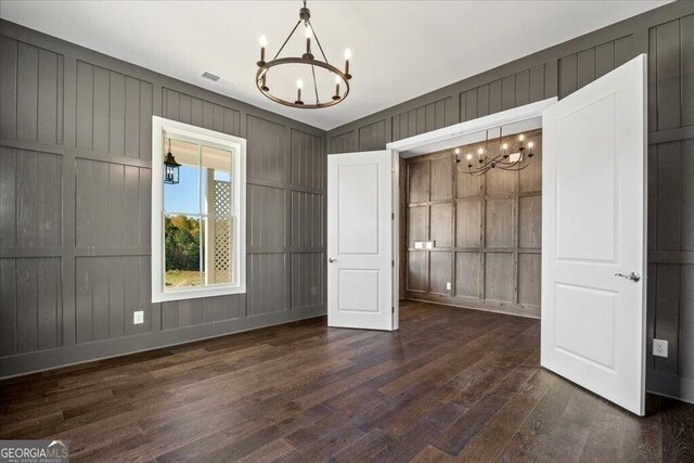 unfurnished living room featuring dark wood-type flooring, an inviting chandelier, french doors, crown molding, and beam ceiling