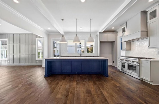 kitchen featuring range with two ovens, dark wood-style flooring, light countertops, decorative backsplash, and custom range hood