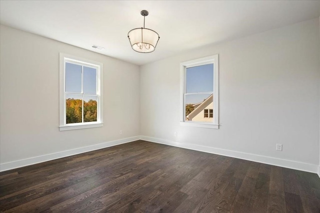 unfurnished room with dark wood-style floors, visible vents, and baseboards