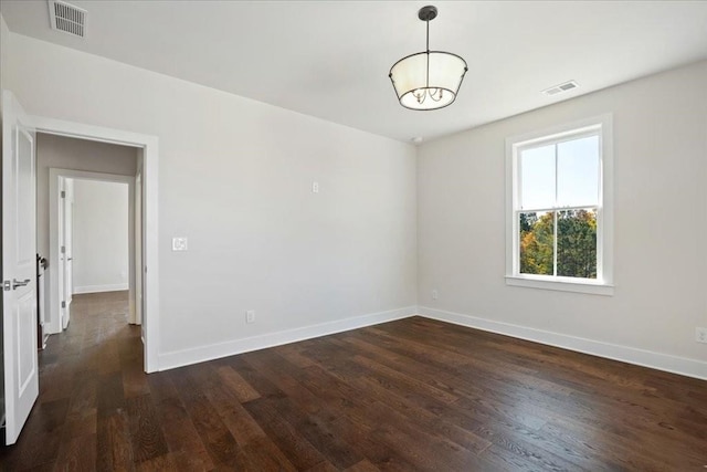 spare room featuring visible vents, baseboards, and wood finished floors