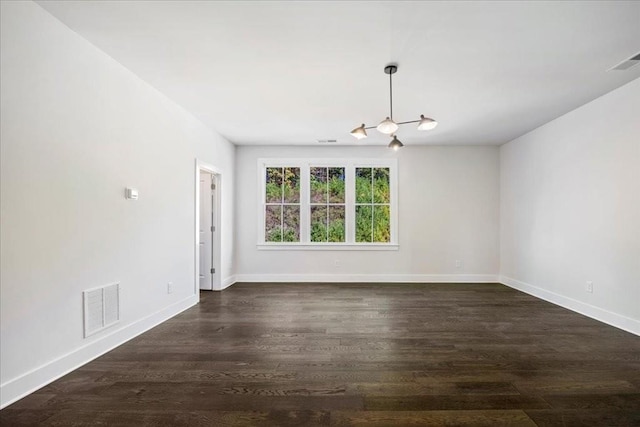 spare room with dark wood-style floors, visible vents, and baseboards