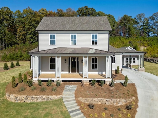 view of front facade with driveway, metal roof, a standing seam roof, a porch, and a front yard