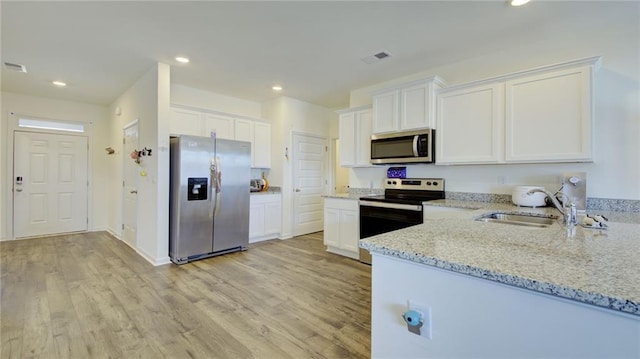 kitchen featuring light hardwood / wood-style floors, white cabinetry, light stone counters, and stainless steel appliances