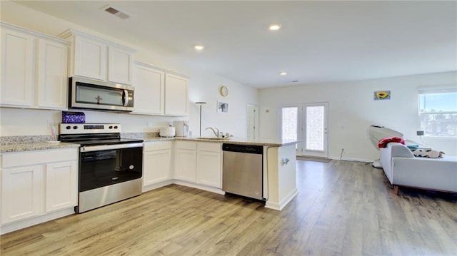 kitchen with light hardwood / wood-style floors, kitchen peninsula, white cabinets, sink, and appliances with stainless steel finishes