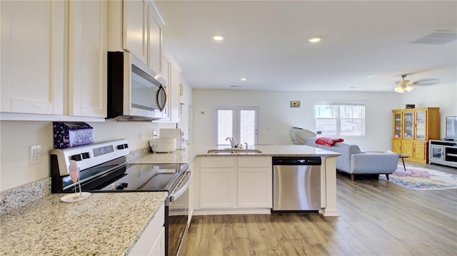 kitchen with ceiling fan, white cabinetry, light wood-type flooring, appliances with stainless steel finishes, and sink