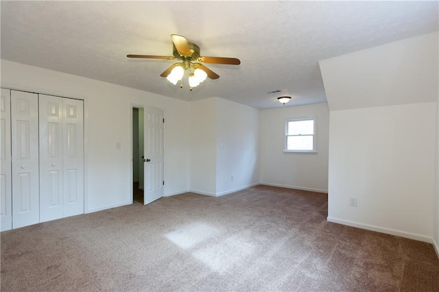 unfurnished bedroom featuring ceiling fan, a textured ceiling, a closet, and carpet flooring