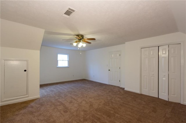 bonus room with ceiling fan and dark carpet