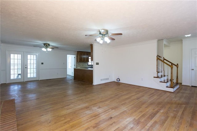 unfurnished living room with hardwood / wood-style floors, ceiling fan, french doors, a textured ceiling, and ornamental molding