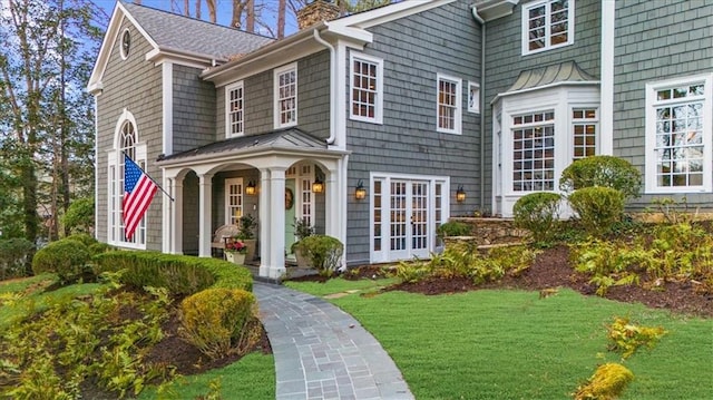 exterior space featuring a lawn, a chimney, and a standing seam roof
