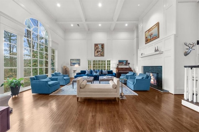 living room featuring beam ceiling, dark wood-style flooring, coffered ceiling, and a lit fireplace