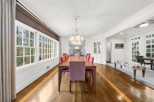 dining area featuring wood finished floors, baseboards, ornamental molding, french doors, and a notable chandelier