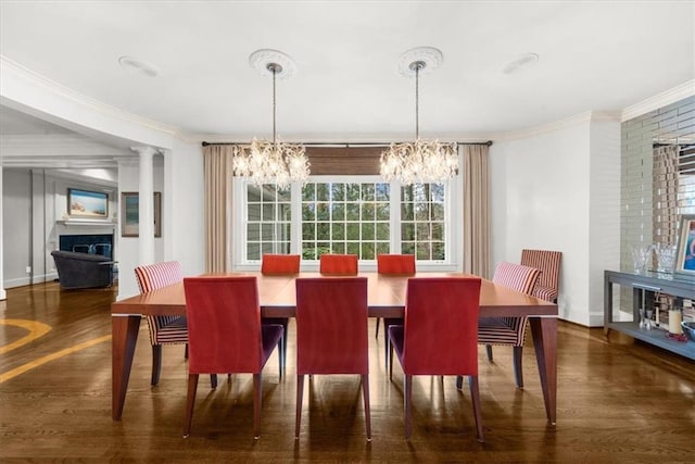 dining space with a fireplace, a notable chandelier, wood finished floors, and crown molding