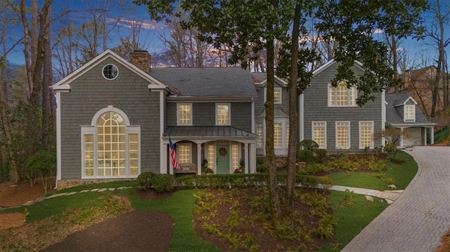 view of front of house with a porch, a chimney, decorative driveway, and a garage