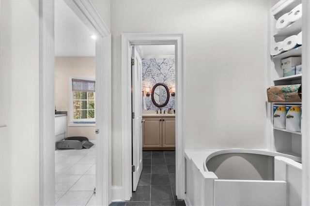 hall featuring a sink and dark tile patterned flooring