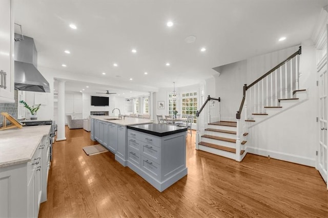 kitchen with a sink, wood finished floors, open floor plan, ventilation hood, and recessed lighting