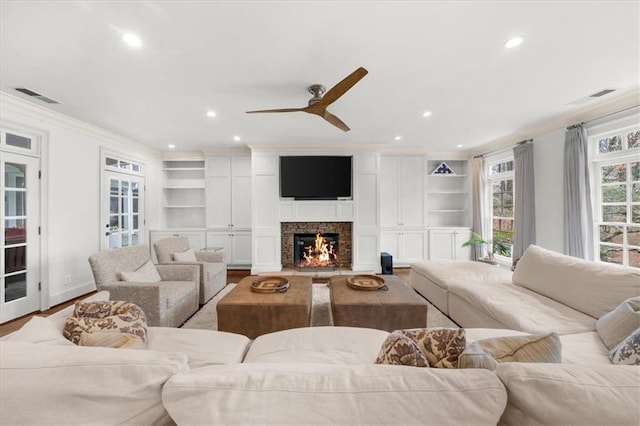 living room with visible vents, built in shelves, and crown molding