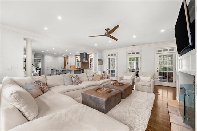living room with ornate columns, crown molding, ceiling fan, and wood finished floors