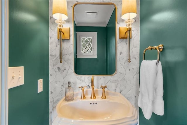 bathroom with ornamental molding, wallpapered walls, and a sink
