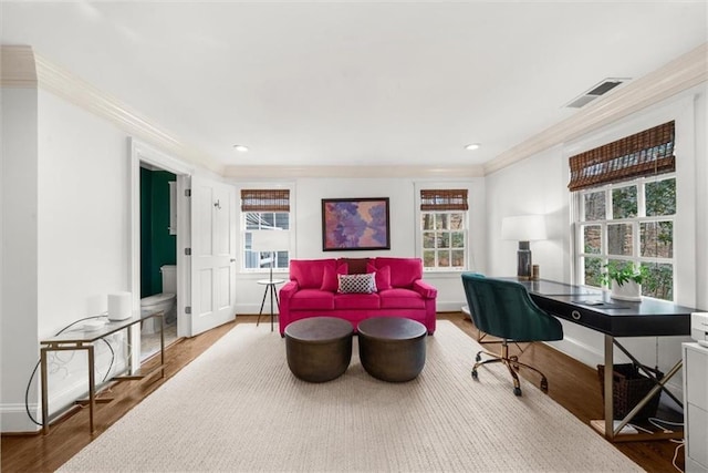living area with wood finished floors, baseboards, visible vents, recessed lighting, and ornamental molding