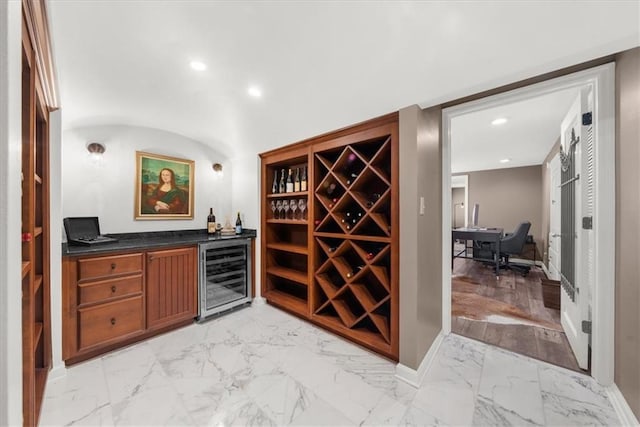 wine room with marble finish floor, beverage cooler, recessed lighting, baseboards, and a dry bar