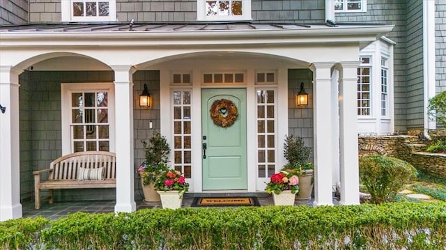 doorway to property featuring a standing seam roof, a porch, and metal roof