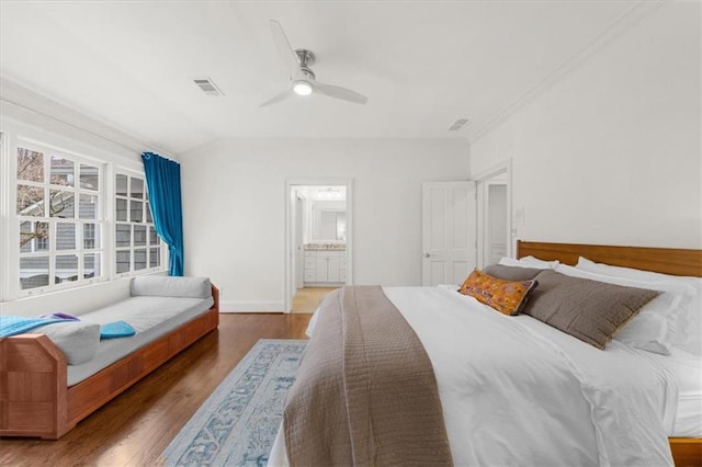 bedroom with visible vents, baseboards, ceiling fan, ensuite bathroom, and wood finished floors
