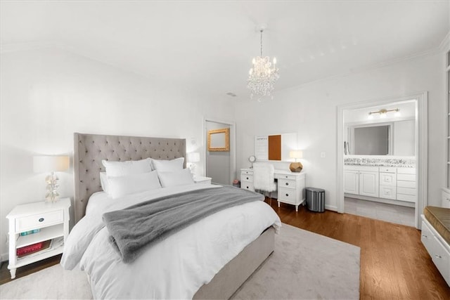 bedroom featuring a notable chandelier, wood finished floors, and ensuite bathroom