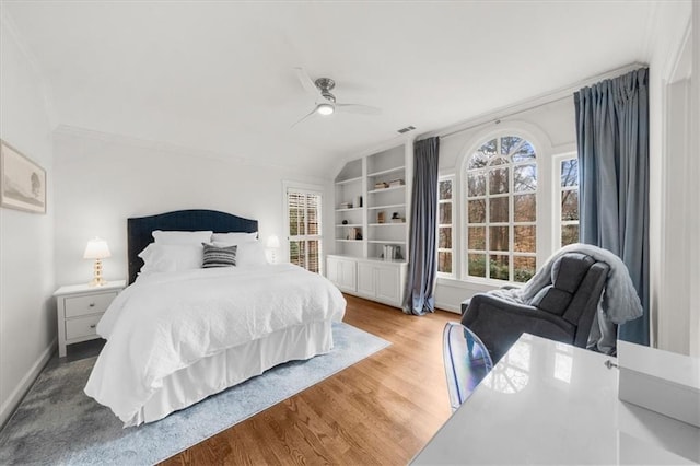 bedroom featuring visible vents, ornamental molding, wood finished floors, baseboards, and ceiling fan