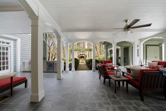 view of patio featuring a ceiling fan and an outdoor living space with a fireplace
