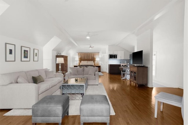 living area featuring lofted ceiling, a ceiling fan, and wood finished floors
