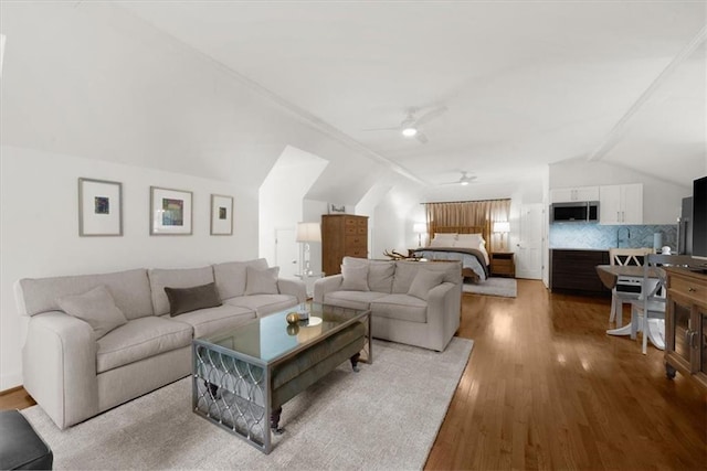 living room featuring wood finished floors, a ceiling fan, and vaulted ceiling