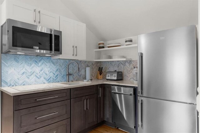 kitchen featuring a sink, lofted ceiling, white cabinets, stainless steel appliances, and open shelves