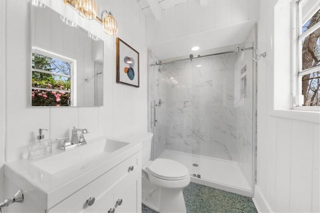 bathroom featuring a marble finish shower, toilet, a healthy amount of sunlight, and vanity